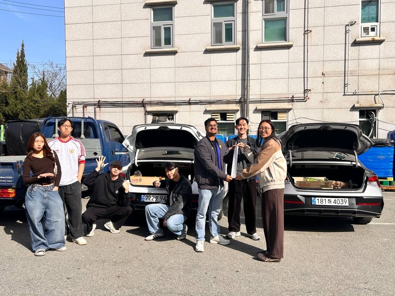 Friends gathered around two cars on a road trip in Korea